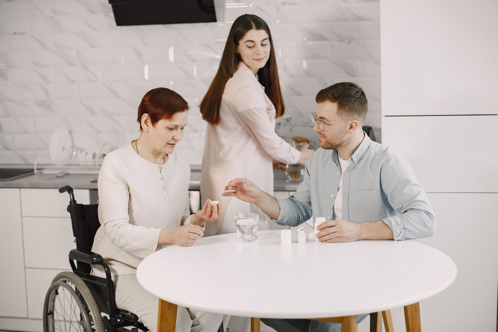 Family caregivers helping a woman in a wheelchair with her medication