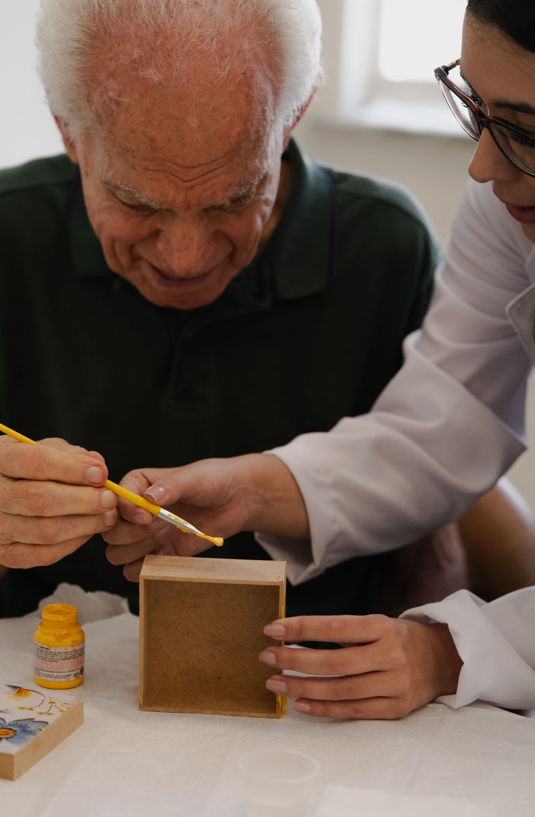 A caregiver helping a senior with an art activity